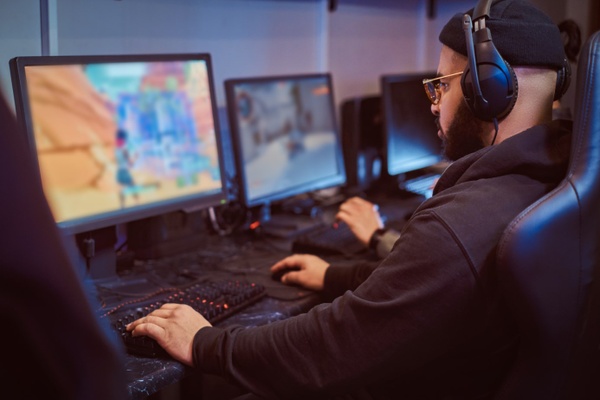 Premium Photo  Player feeling happy after winning video games on computer.  man celebrating online win and playing games with headphones and monitor.  gamer using gaming technology and equipment.